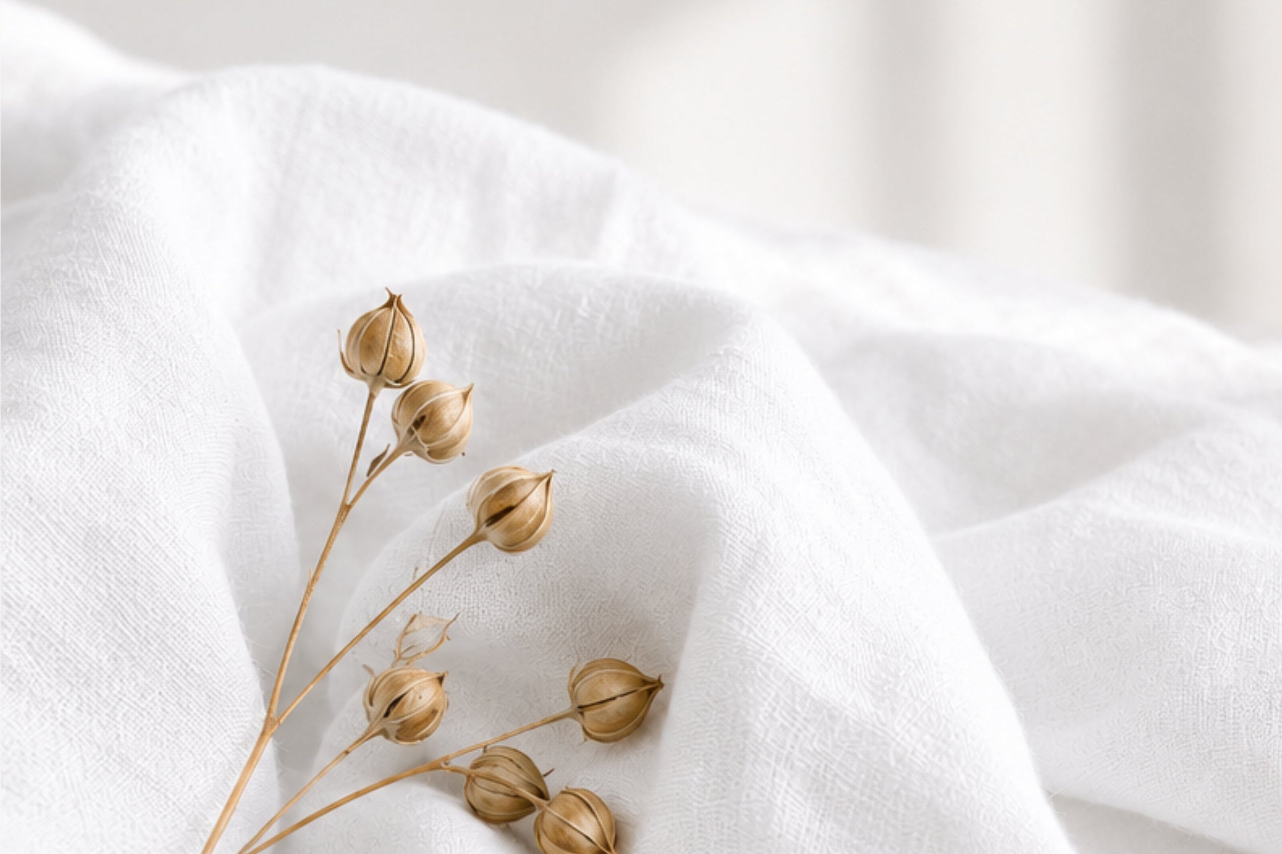 White fabric with dried flowers and text about French flax linen on a white background